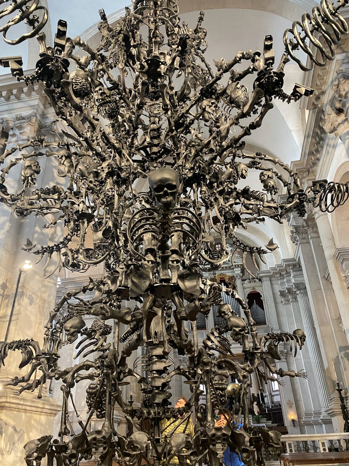 Ai Weiwei, La Commedia Umana, 2022, Installation in San Giorgio Maggiore, schwarzer Glasleuchter, Muranoglas, Kronleuchter, Knochen, Totenköpfe aus Glas, Twittervögel, Überwachungskamera