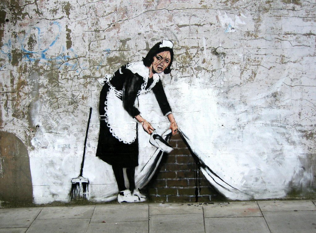 Banksys künstlerischer Aktivismus begeistert die Welt – Graffiti oder Kunst? Zimmermädchen fegt Dreck unter den hochgehobenen Vorhang, Banksy Graffiti 