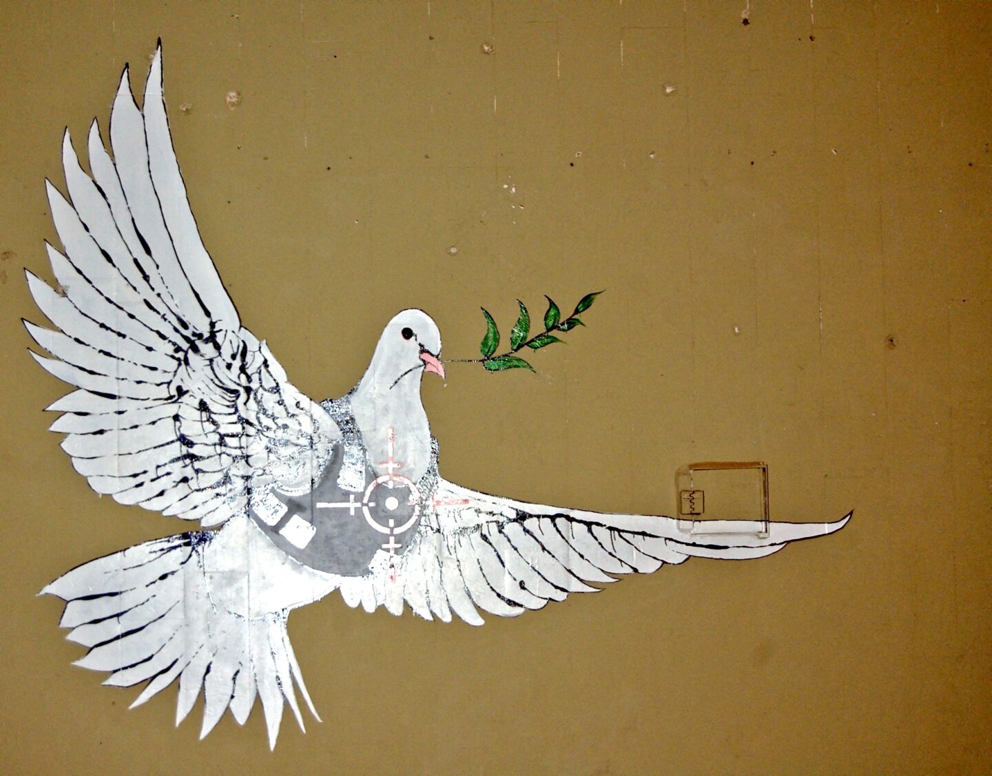 Friedenstaube mit schusssicherer Weste als graffito auf Hauswand, banksy